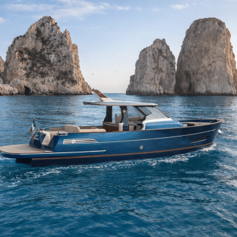 Luxury yacht on blue water with rocky cliffs in background.