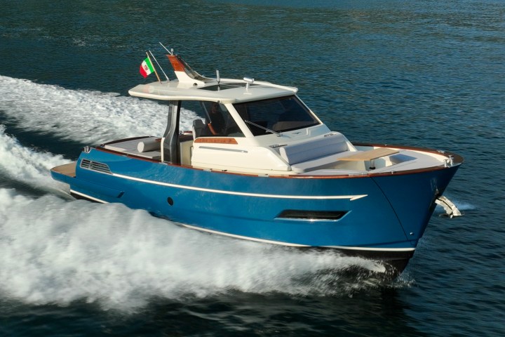 Blue motorboat with a flag, speeding on open water.
