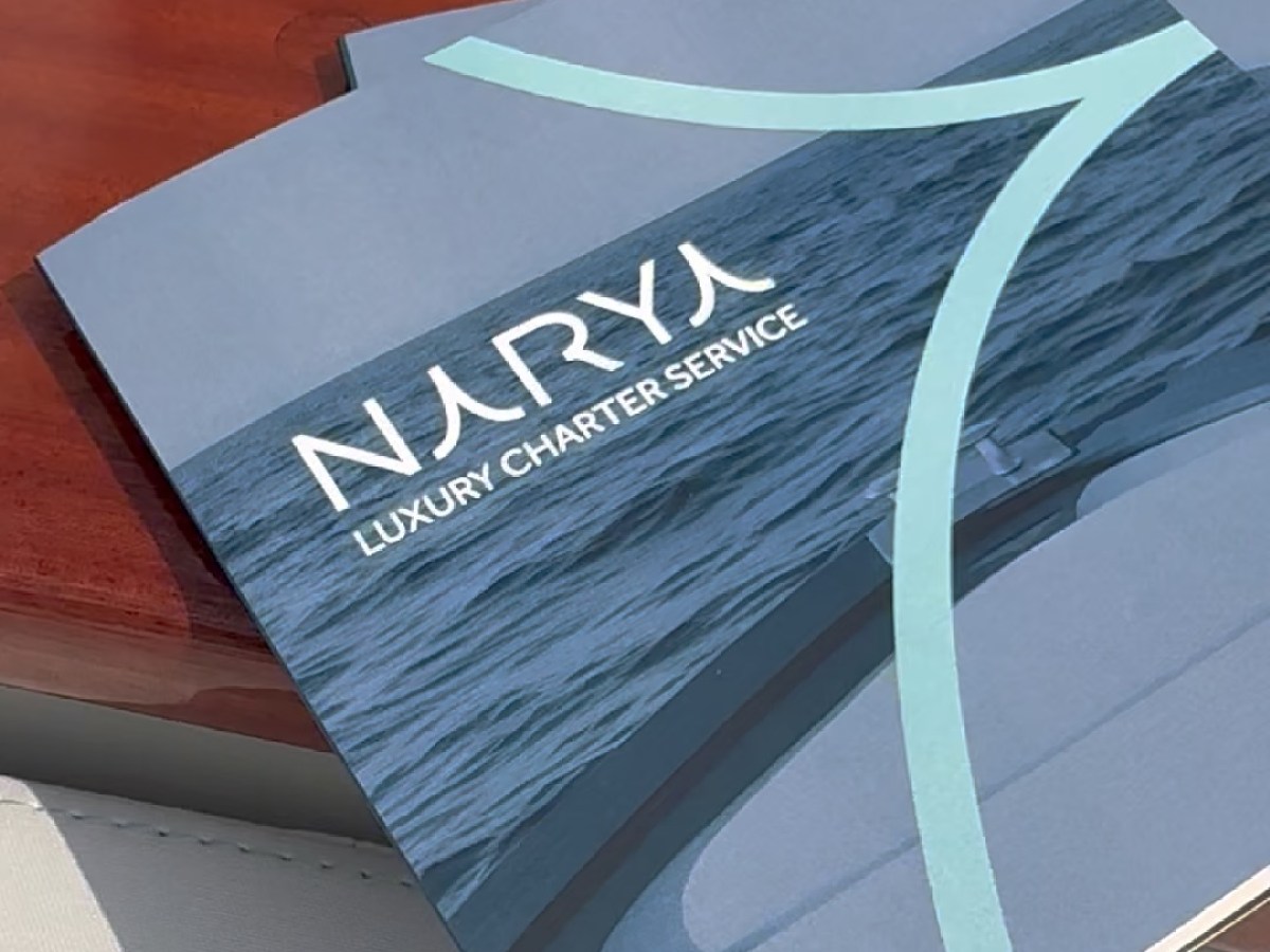 Brochure titled 'Narya Luxury Charter Service' on a yacht surface.