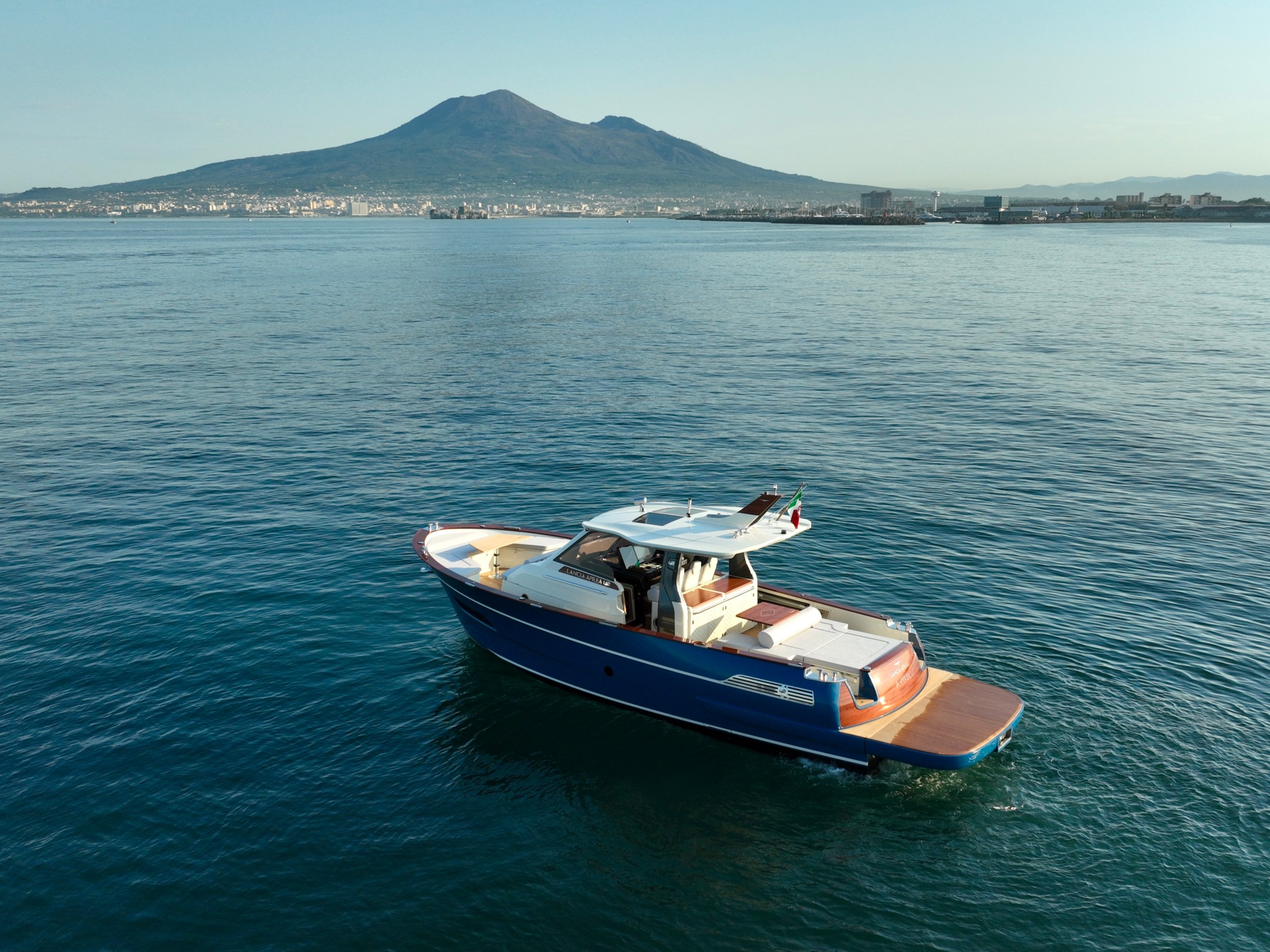 Small boat on water with a volcano in the background.